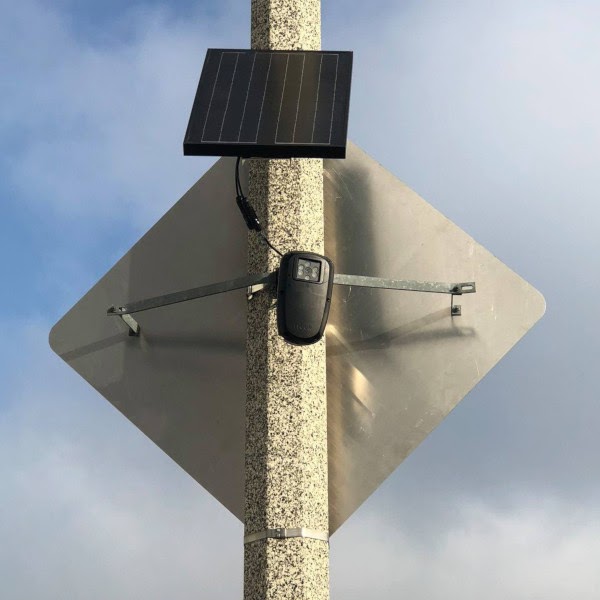 Flock brand automated license plate reader affixed to a light pole.